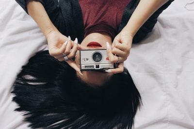 女人躺在红色和黑色控股银点和拍摄相机
